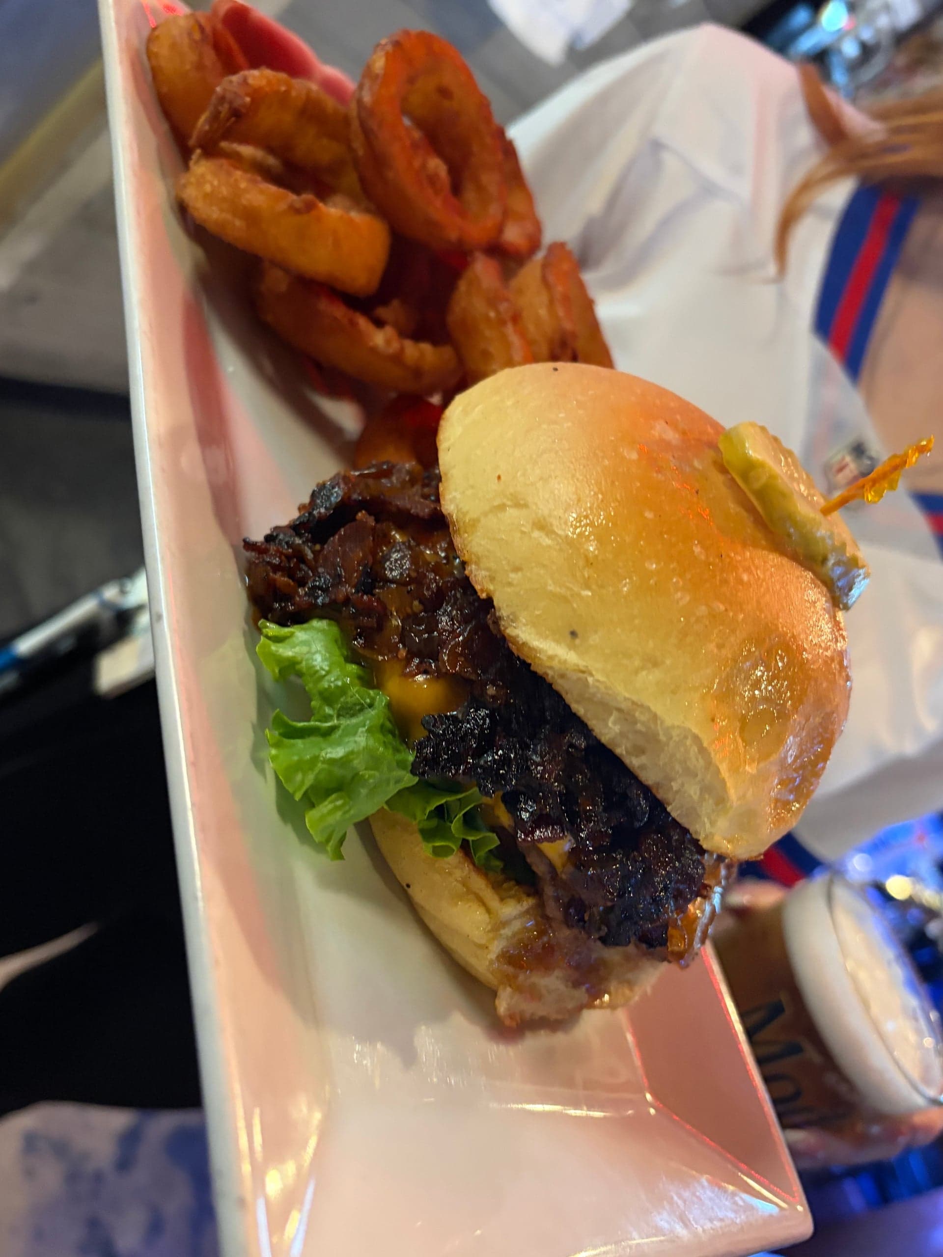 Bacon-jam cheeseburger with lettuce and a pickle on a toasted bun, served with crispy onion ringz.