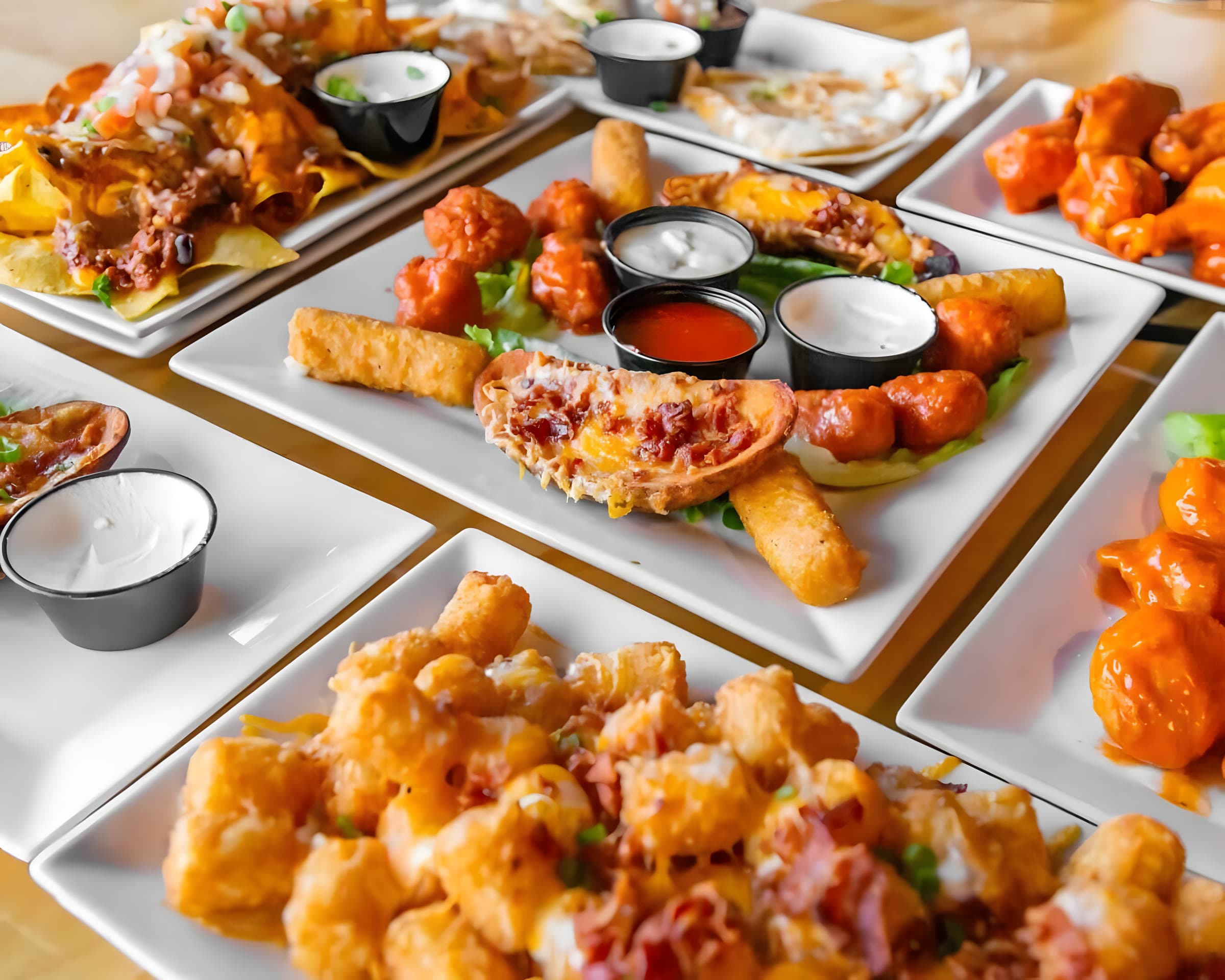 A table spread of nachoz, wingz, potato skinz, mozzarella stickz and loaded tater totz at Canz Bohemia