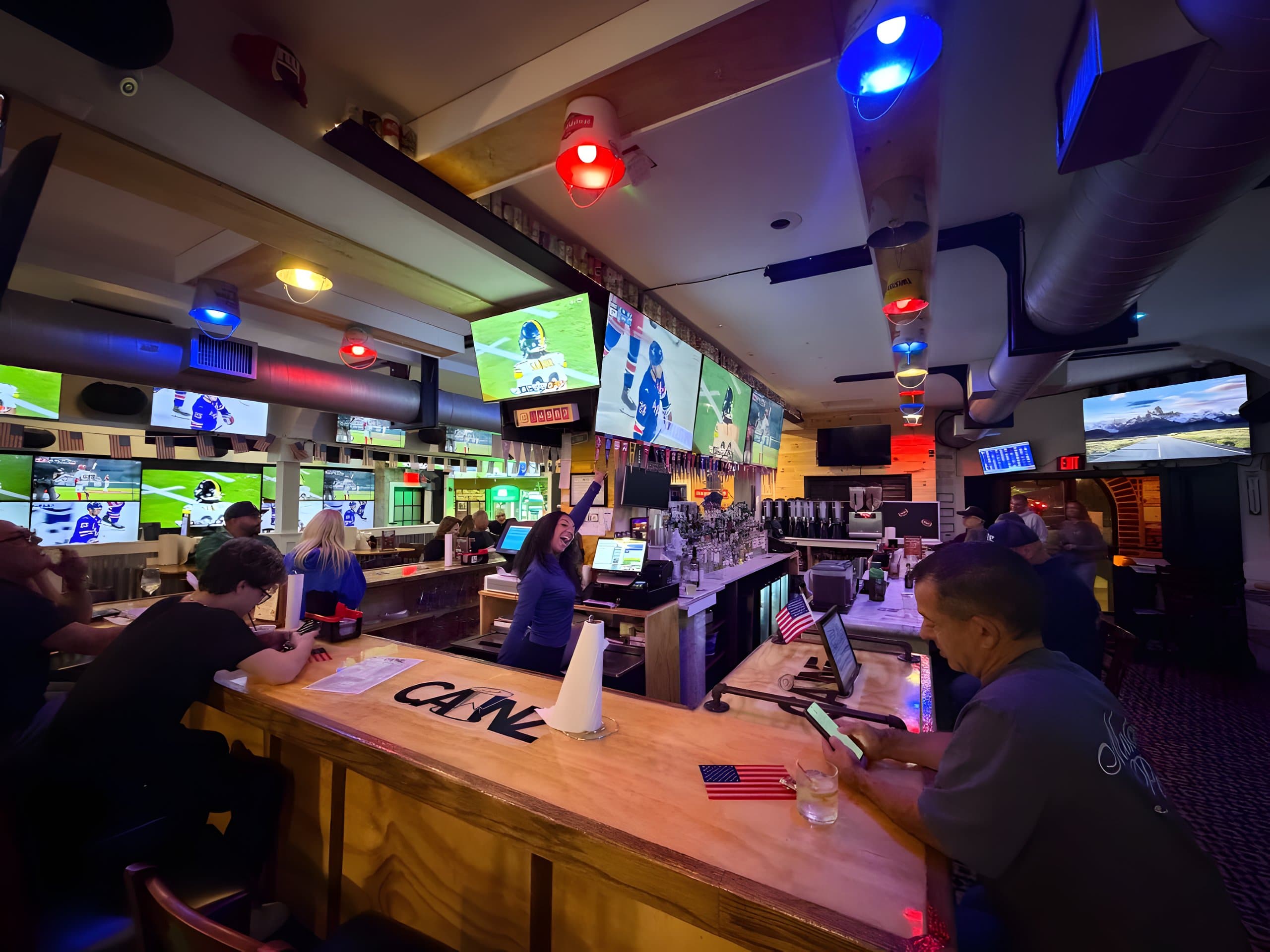 The bartender cheering under the game-day screens at Canz Long Beach