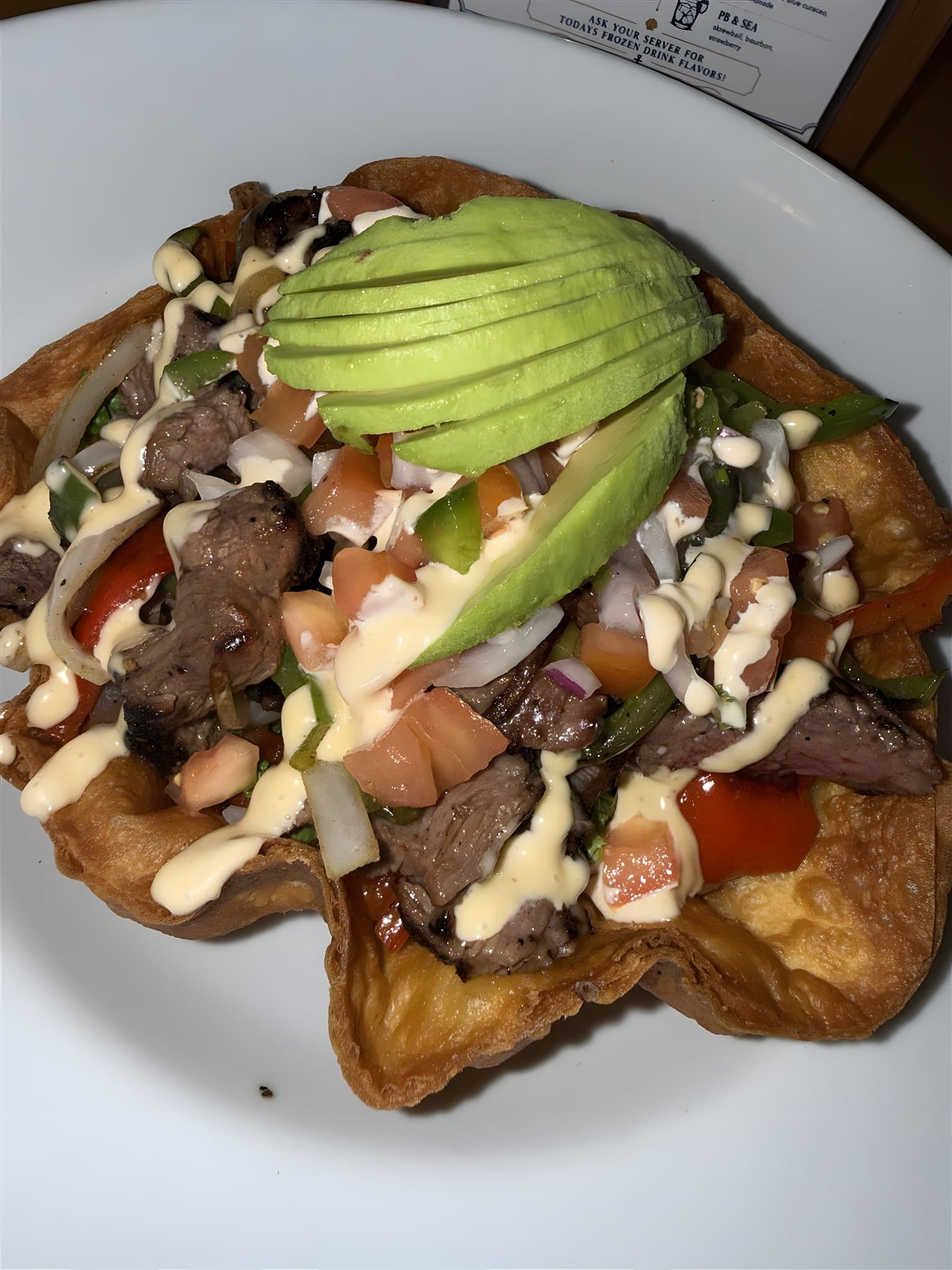Steak taco salad with avocado in a crispy tortilla bowl