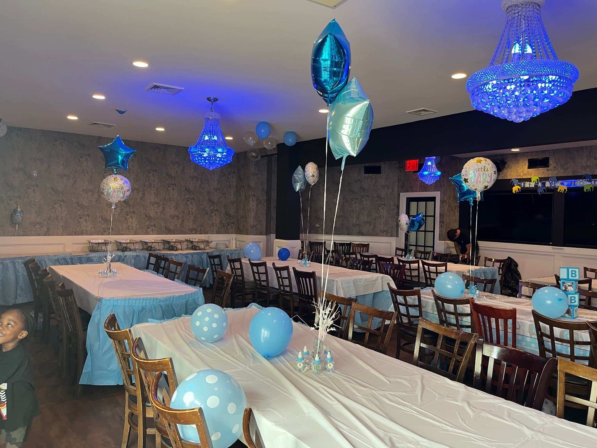 The Ocean Room set for a baby shower, with blue balloons and crystal chandeliers glowing blue
