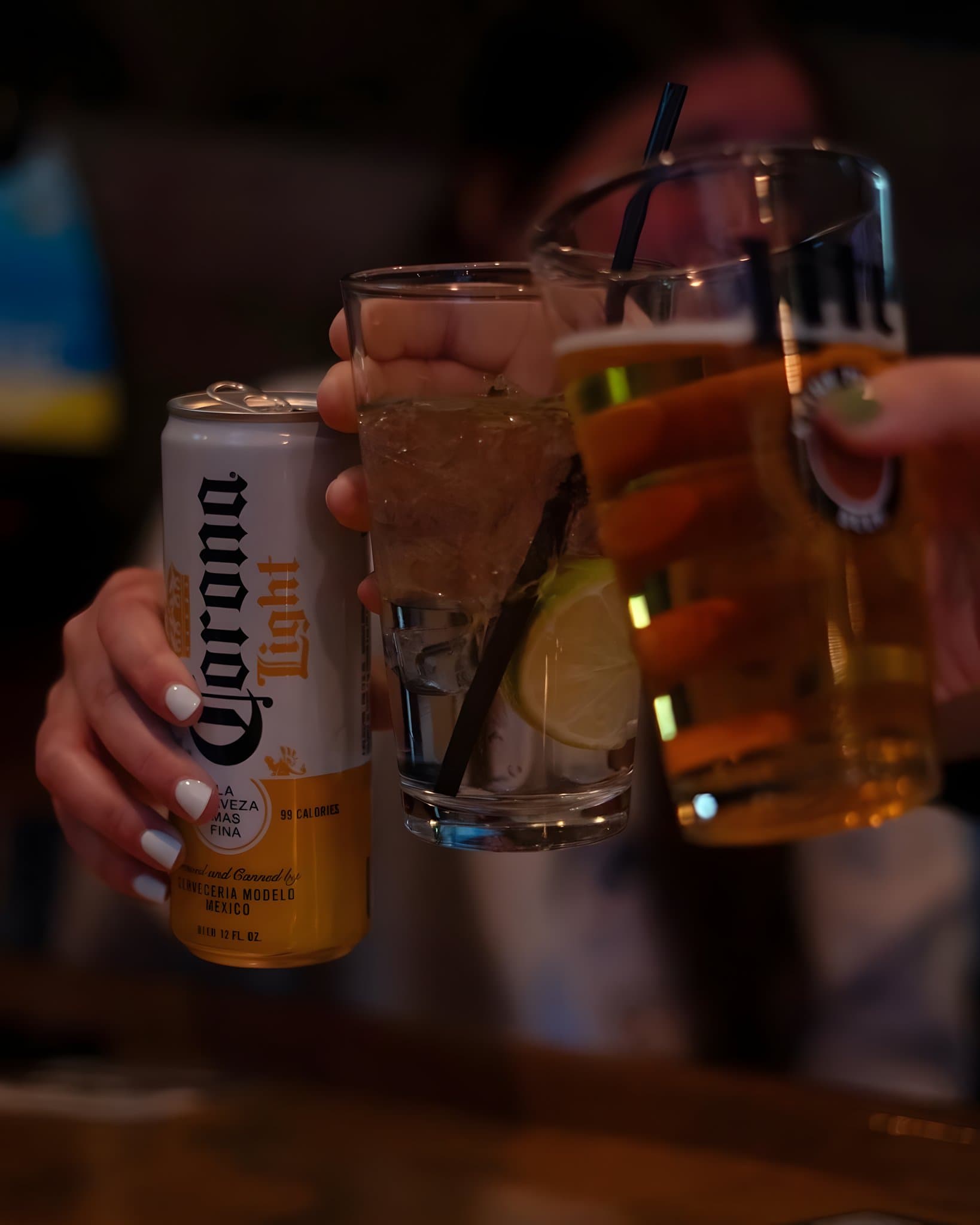Friends toasting with a Corona Light, a mixed drink and a draft beer